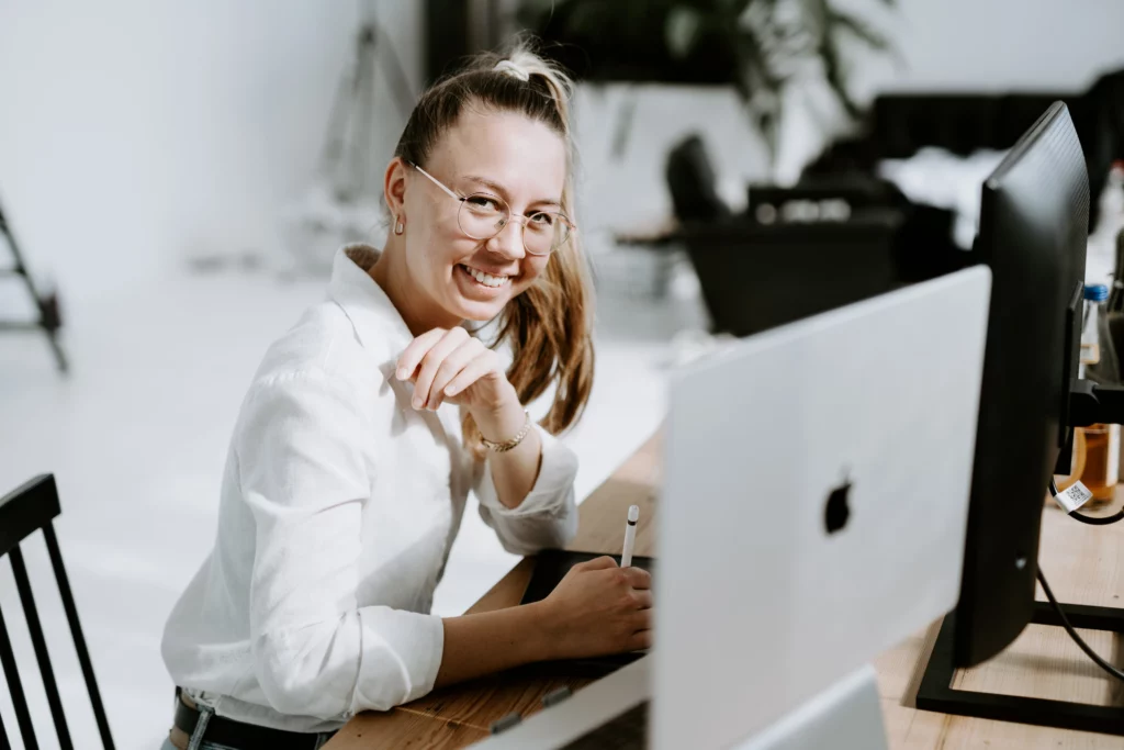 Lächelnde Frau arbeitet am Laptop in einem hellen Büro