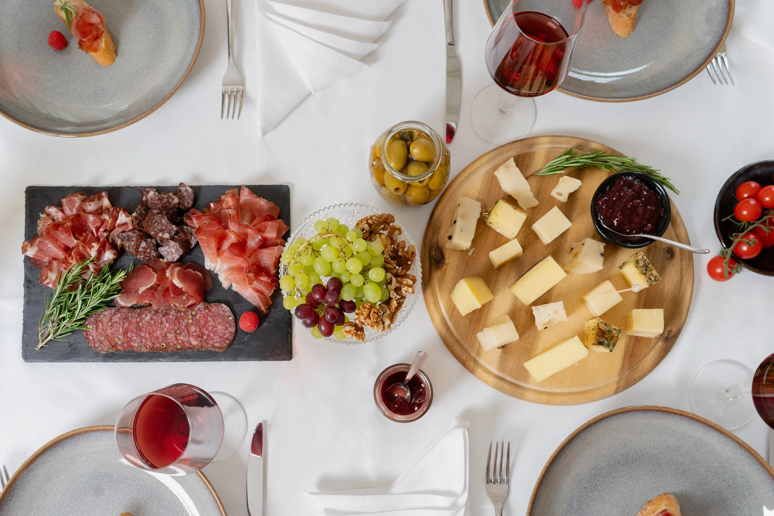 Gedeckter Tisch mit Käse, Schinken, Trauben und Wein von oben