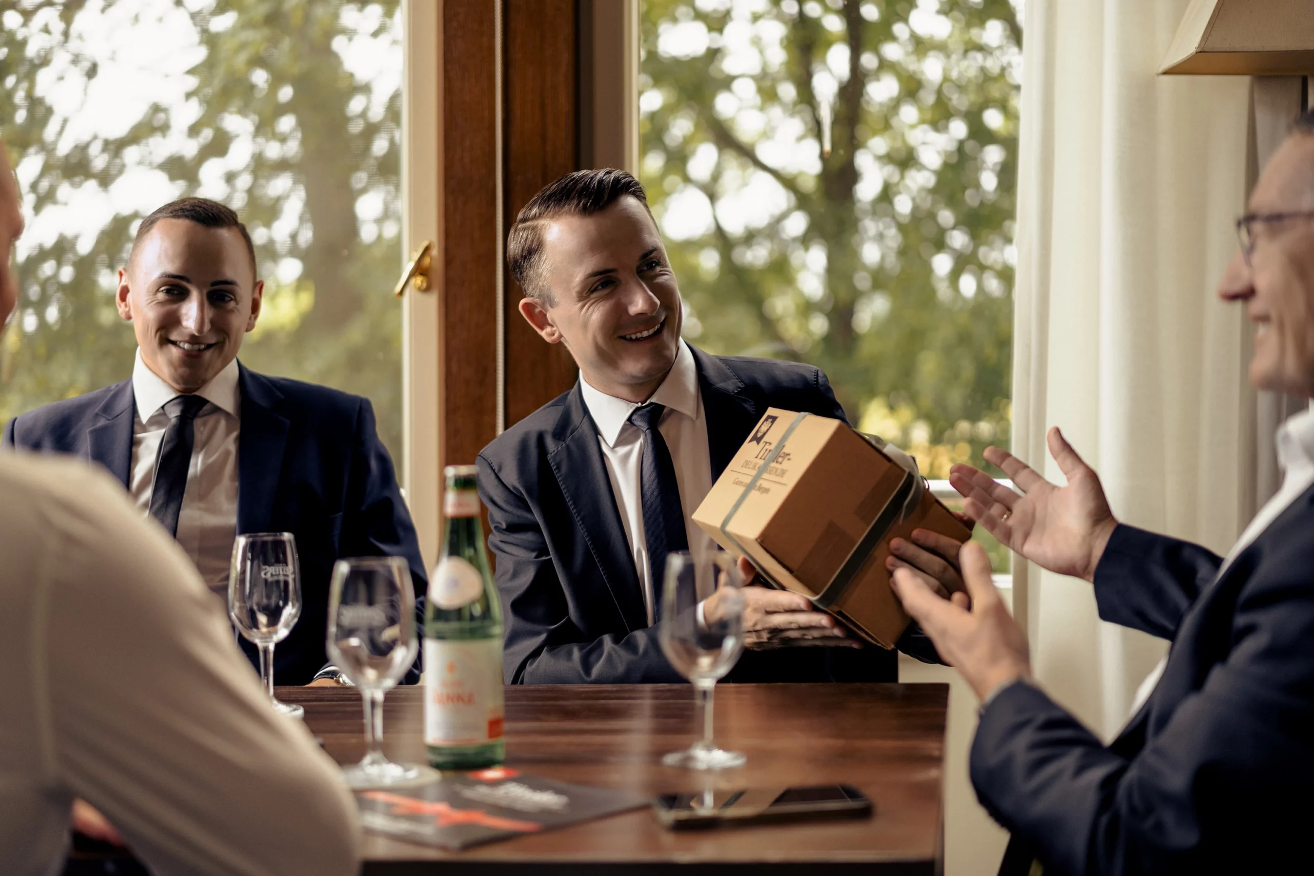 Geschäftsleute stoßen an, dazu eine Geschenkbox von Tiroler Delikatessen