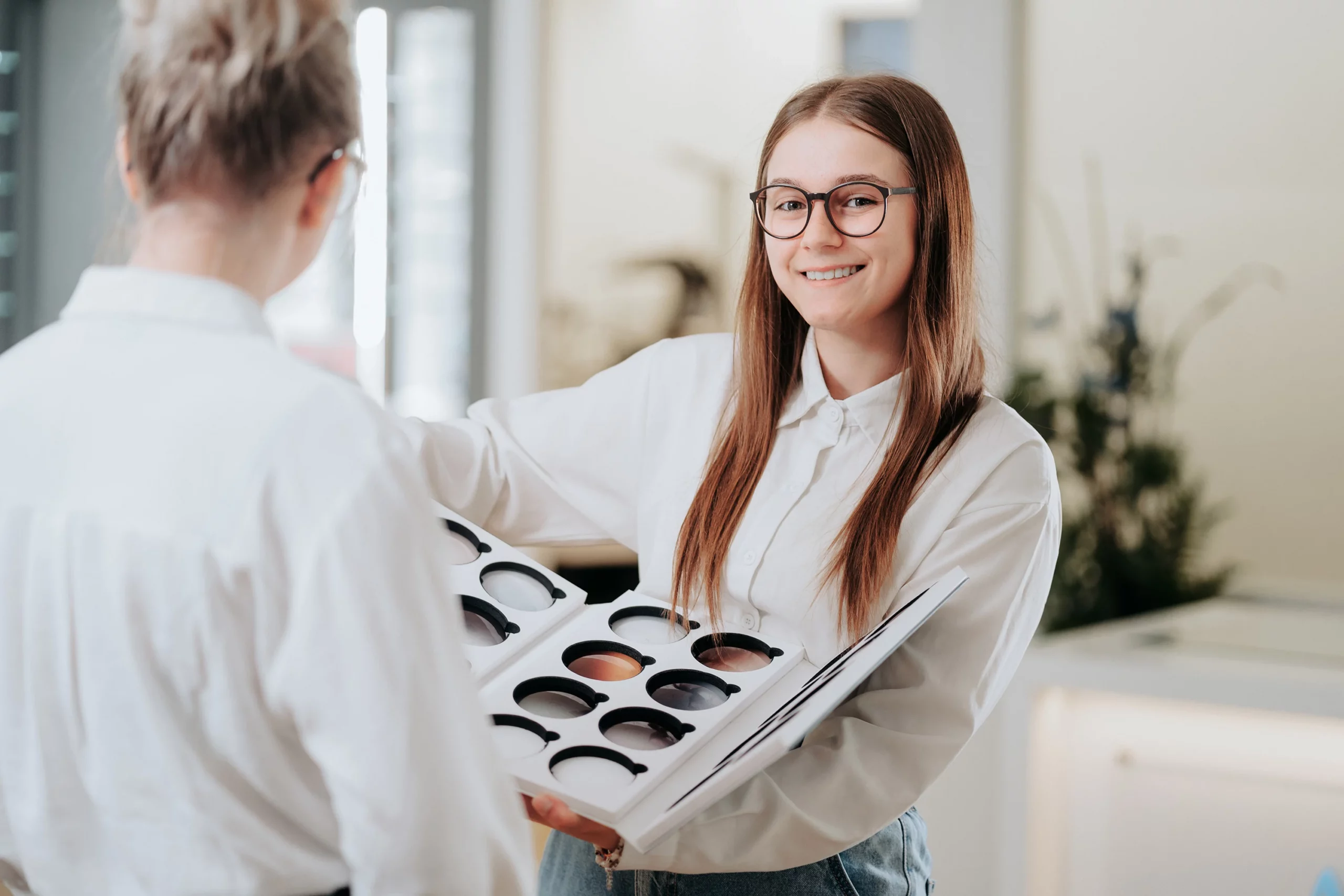 Augenoptikerin zeigt eine Auswahl an Brillengestellen