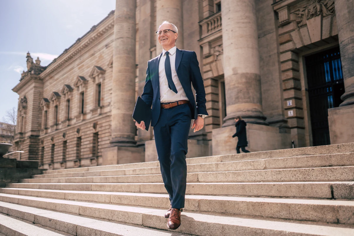 Geschäftsmann im Anzug auf der Treppe eines historischen Gebäudes
