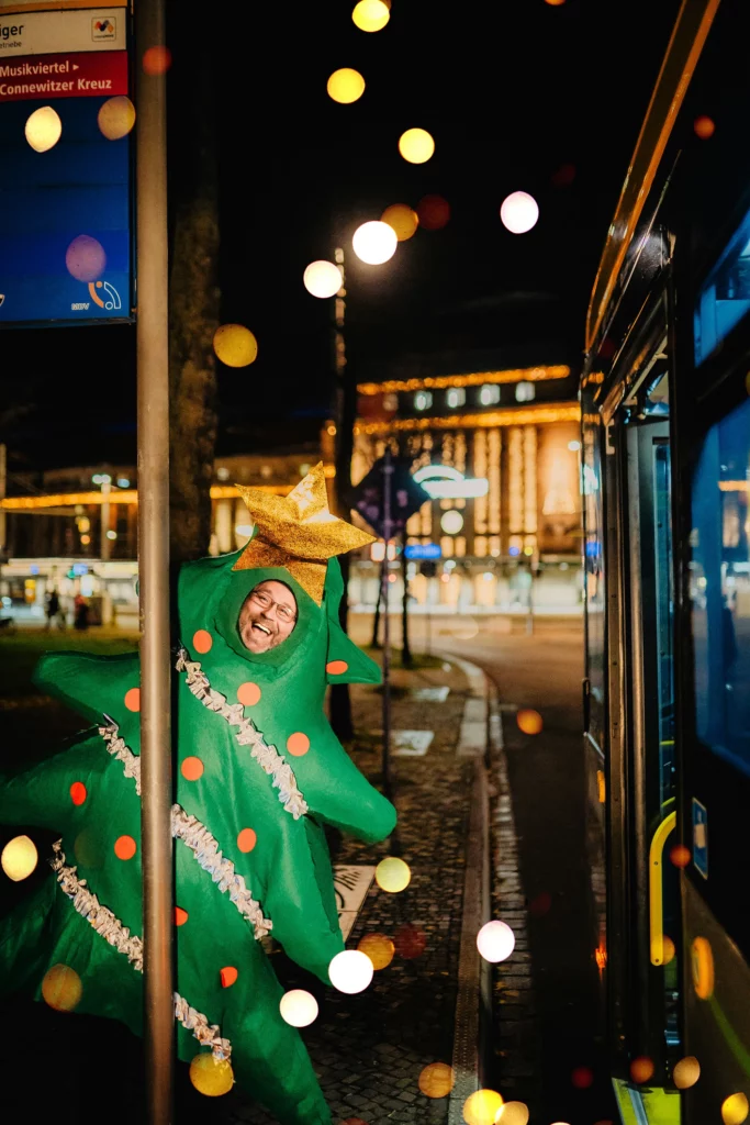 Person im Tannenbaumkostüm an einer Straßenbahn bei Nacht