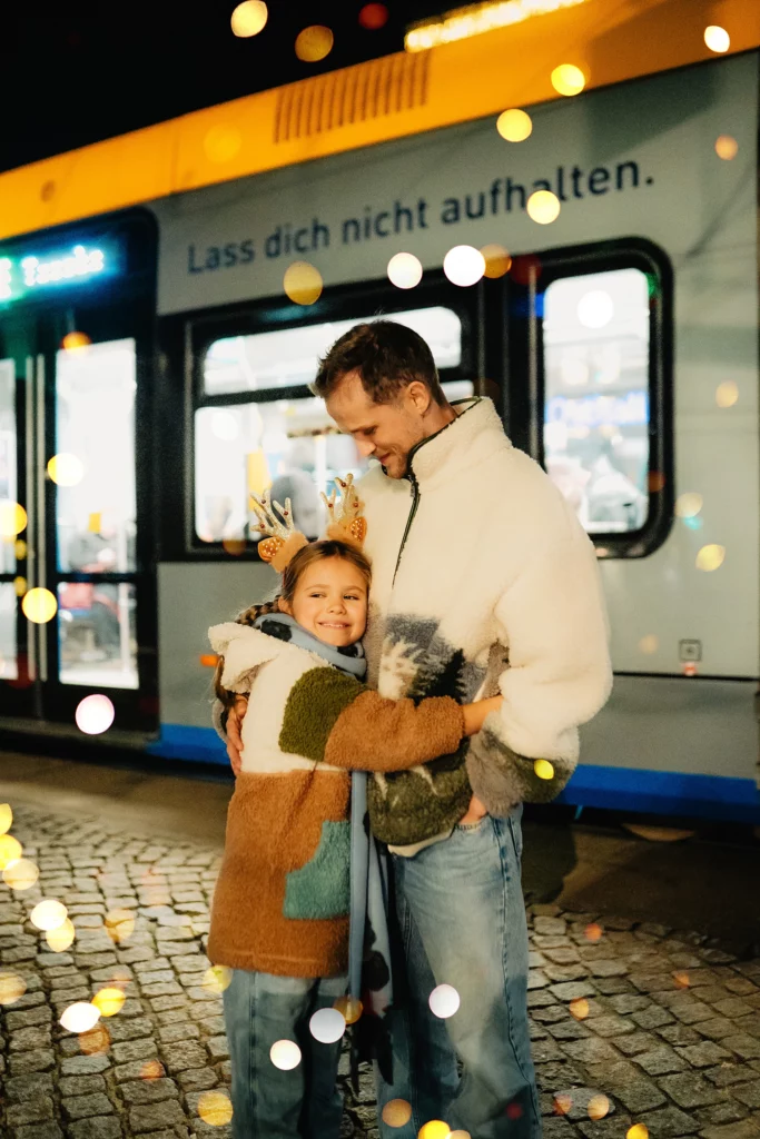 Vater mit Kind an einer Straßenbahnhaltestelle in der Weihnachtszeit