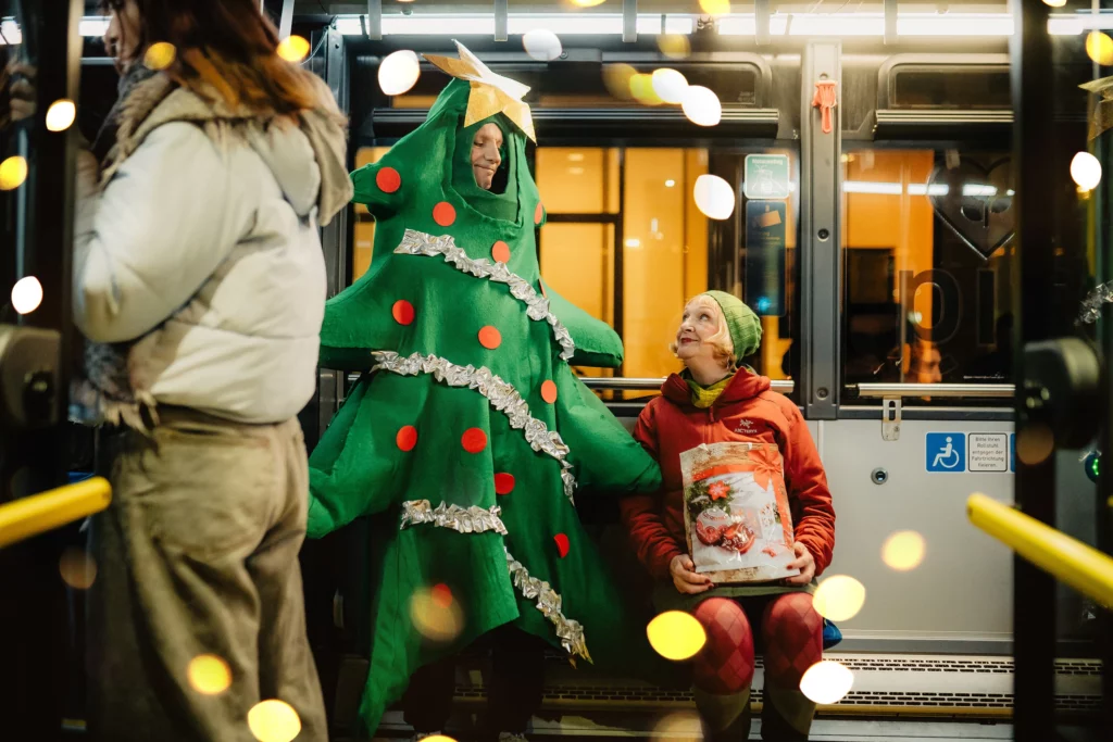 Fahrgäste und eine Person im Tannenbaumkostüm in einer Straßenbahn