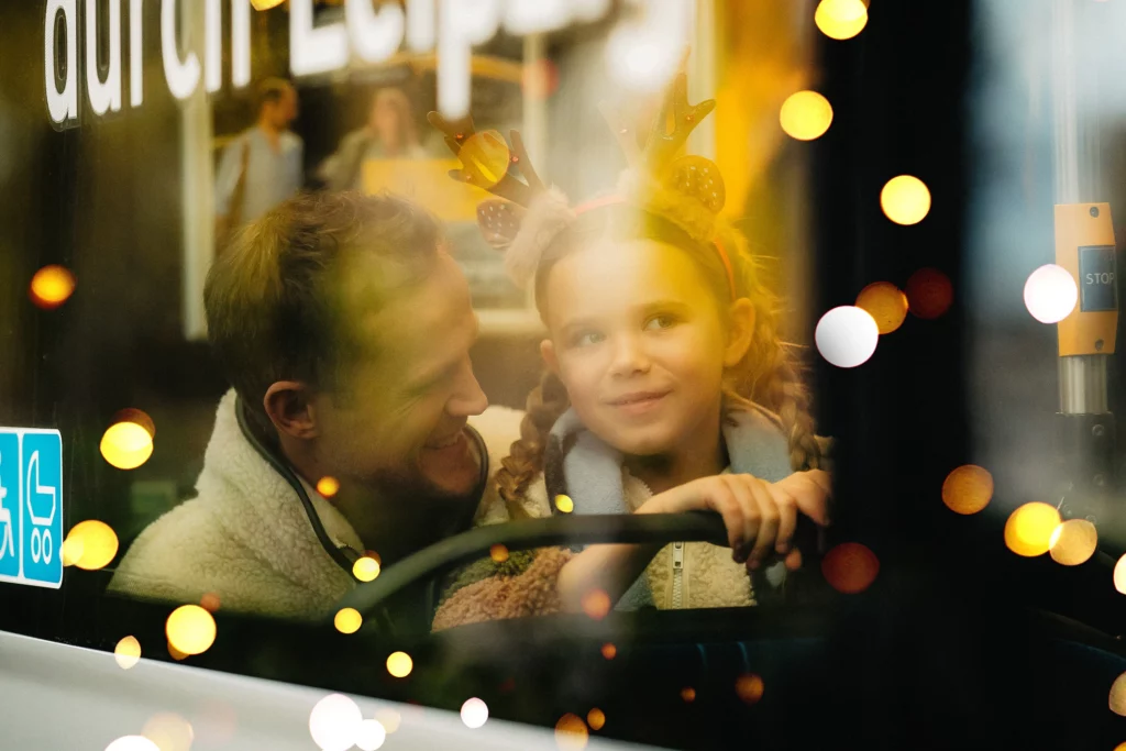 Vater und Tochter hinter der Scheibe einer Straßenbahn mit Lichterglanz