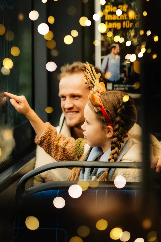 Vater zeigt seiner Tochter aus der Straßenbahn die Weihnachtslichter