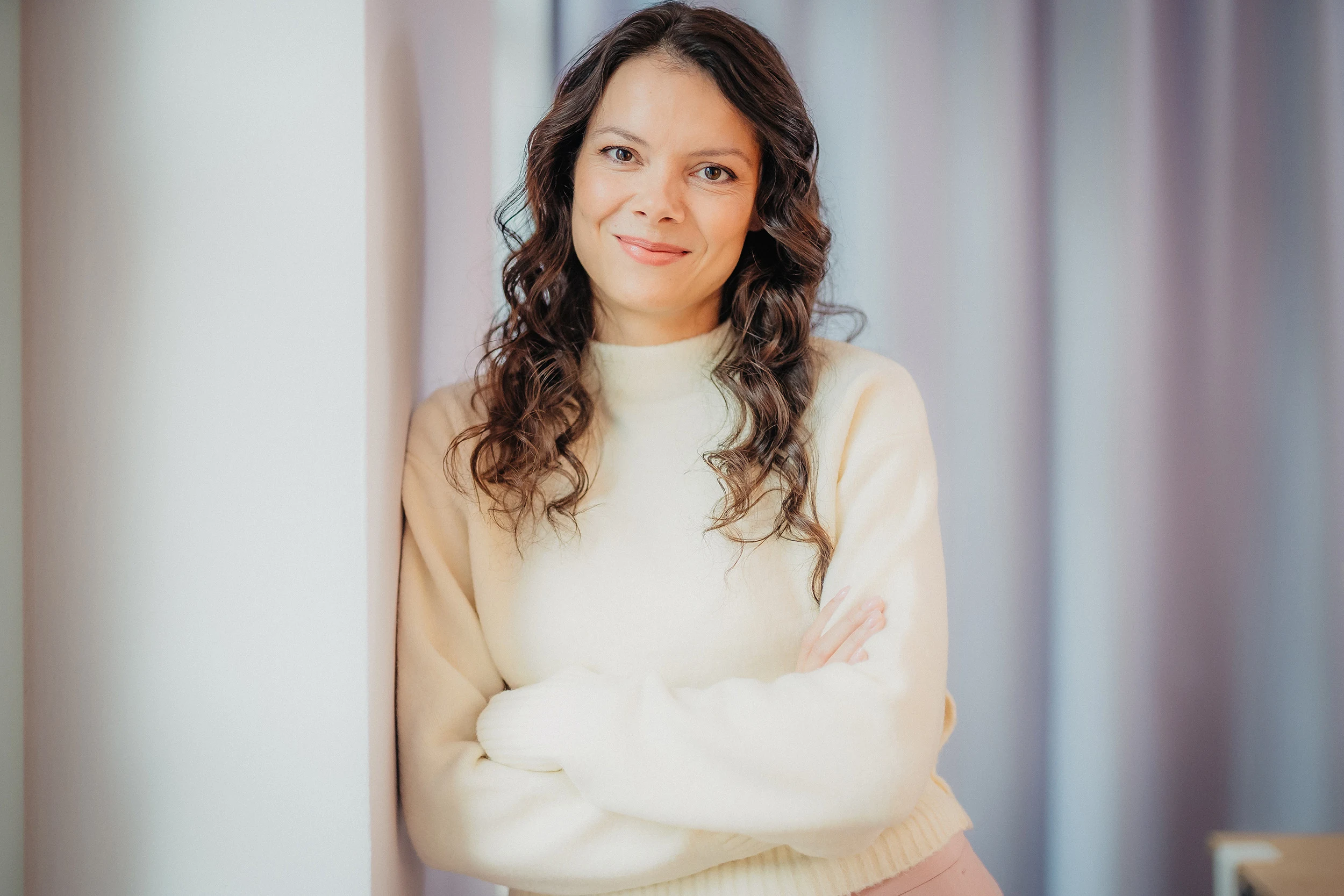 Porträt einer Frau mit Locken im cremefarbenen Pullover