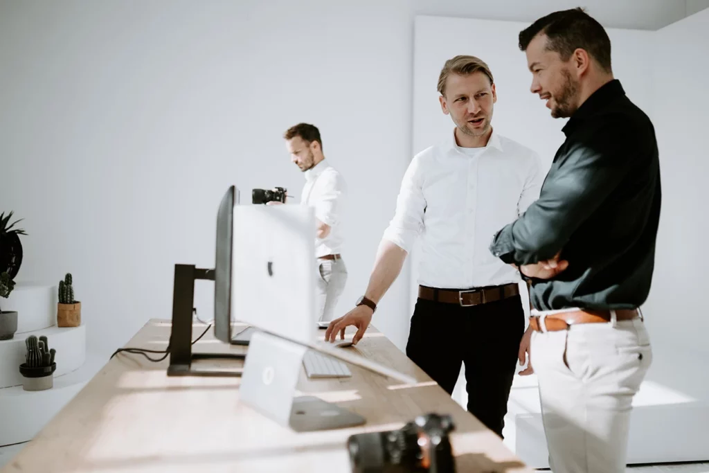 Drei Männer besprechen sich vor einem Bildschirm im Büro