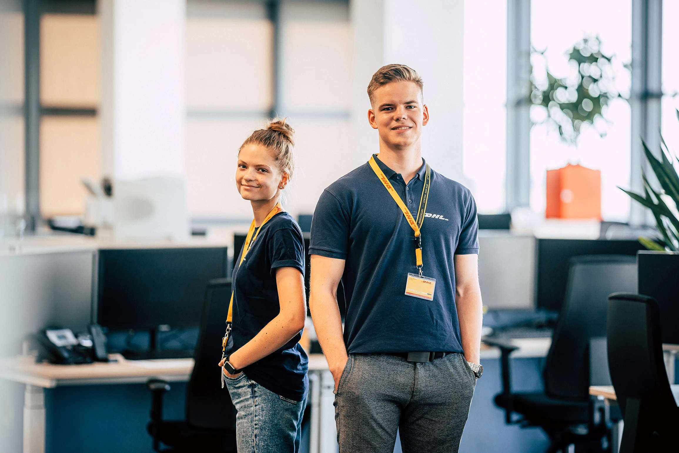 Zwei Mitarbeitende von DHL mit Namensband im Büro