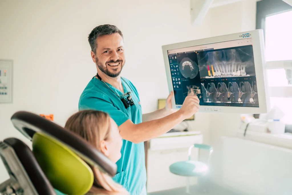 Zahnarzt von Dentale erklärt einem Kind am Bildschirm die Behandlung