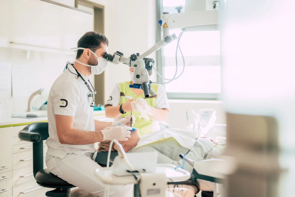 Zahnarzt von Dentale behandelt eine Patientin mit dem Mikroskop
